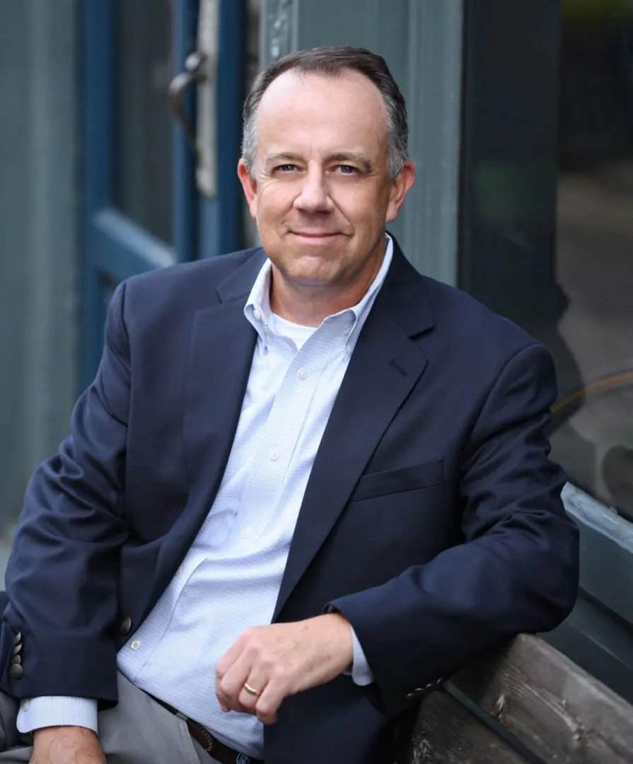 A man in a suit sitting on the ground.